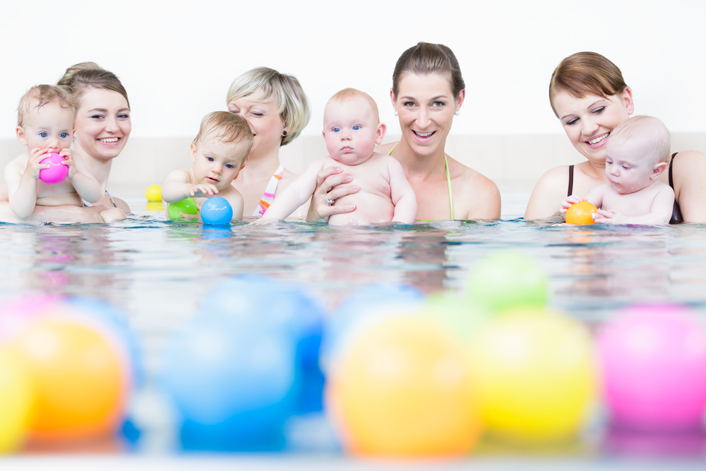 Eltern mit ihren Babys im Babyschwimmkurs